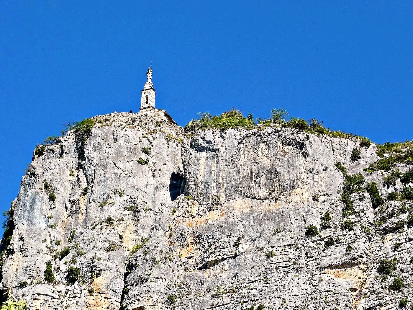Le Roc de Castellane et la chapelle Notre-Dame-du-Roc au sommet de sa falaise calcaire, sous un ciel bleu