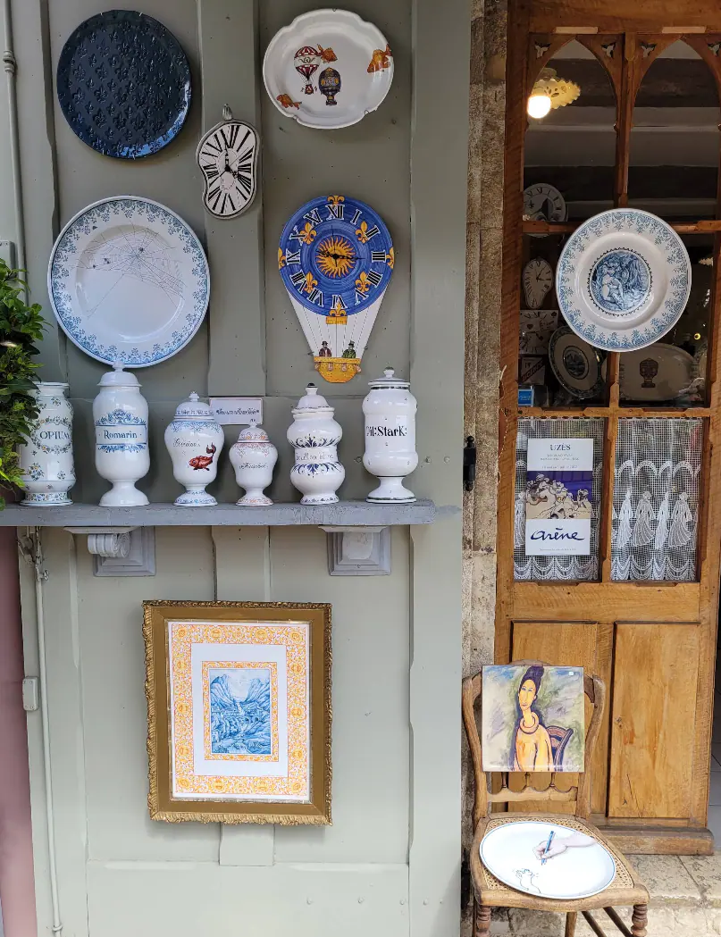 Assiettes, pots d’apothicaire et horloges en faïence exposés dans une rue de Moustiers