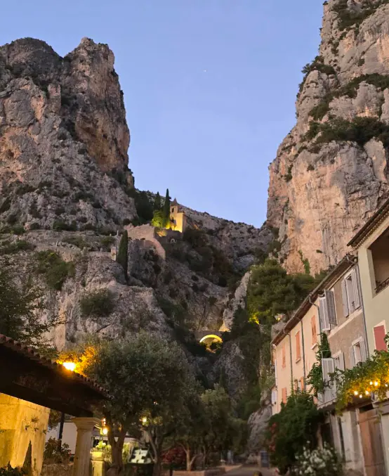 Le village de Moustiers-Sainte-Marie à la tombée de la nuit, au pied des falaises et de la chapelle éclairée