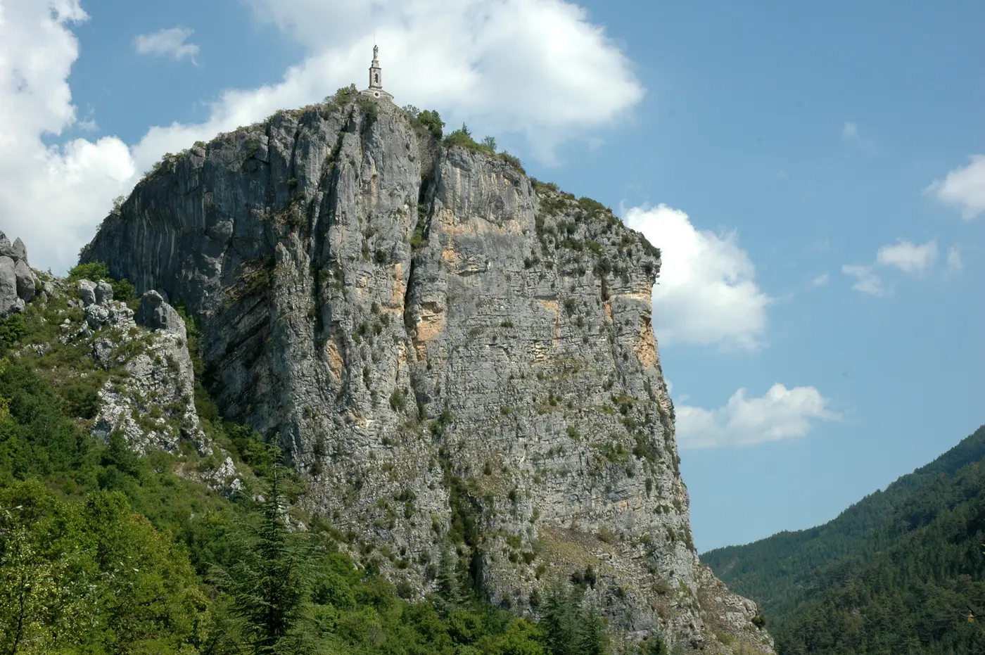 Le Roc de Castellane, piton calcaire couronné par la chapelle Notre-Dame-du-Roc, dominant la porte est des Gorges du Verdon sous un ciel bleu