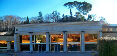 La colonnade de l'entrée des thermes de Gréoux-les-Bains sous le soleil de février, avec les pins parasols
