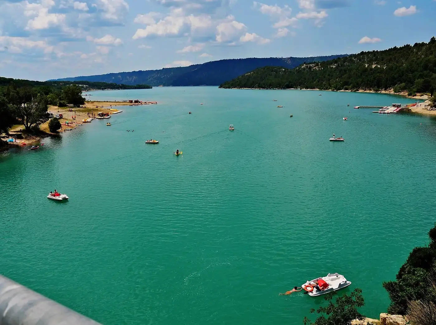 Pédalos et baigneurs sur les eaux turquoise du lac de Sainte-Croix, entre deux rives boisées
